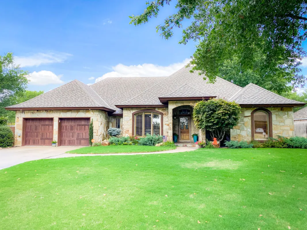 Stone home with a two-car garage and a green lawn